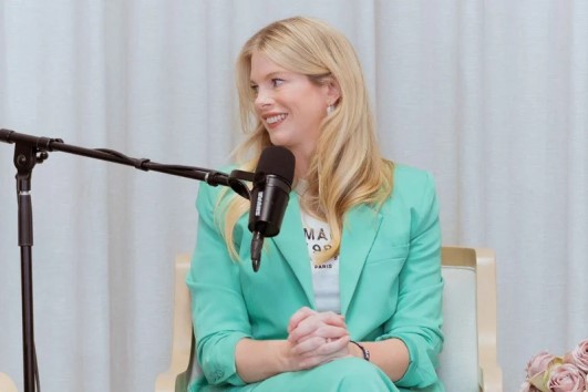 Beth Clay speaking into a microphone in a mint suit